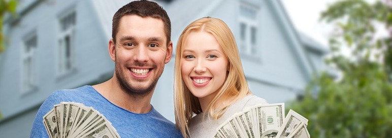 love, people, real estate, home and family concept - smiling couple showing dollar cash money over house background